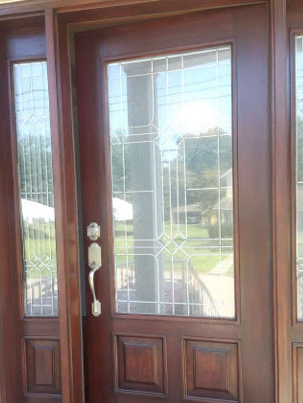 Elegant wooden door with glass panels featuring intricate geometric designs.