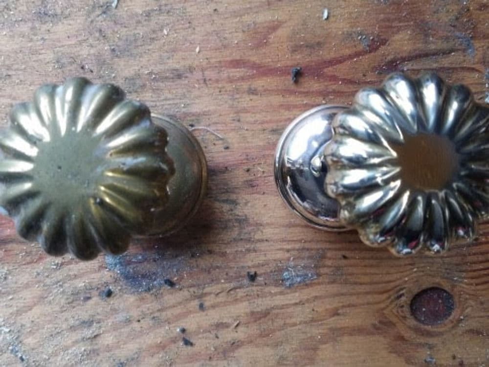 Close-up of vintage brass door knobs on wooden surface, showcasing intricate designs.