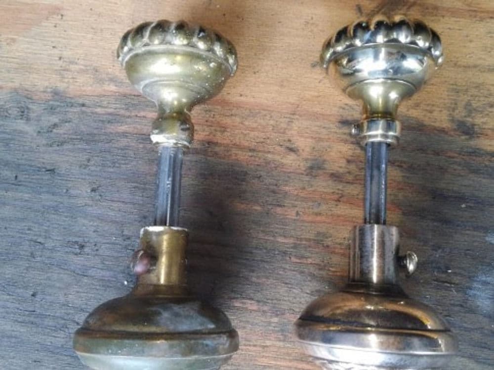 Vintage brass curtain rod ends with decorative finials on wooden surface.