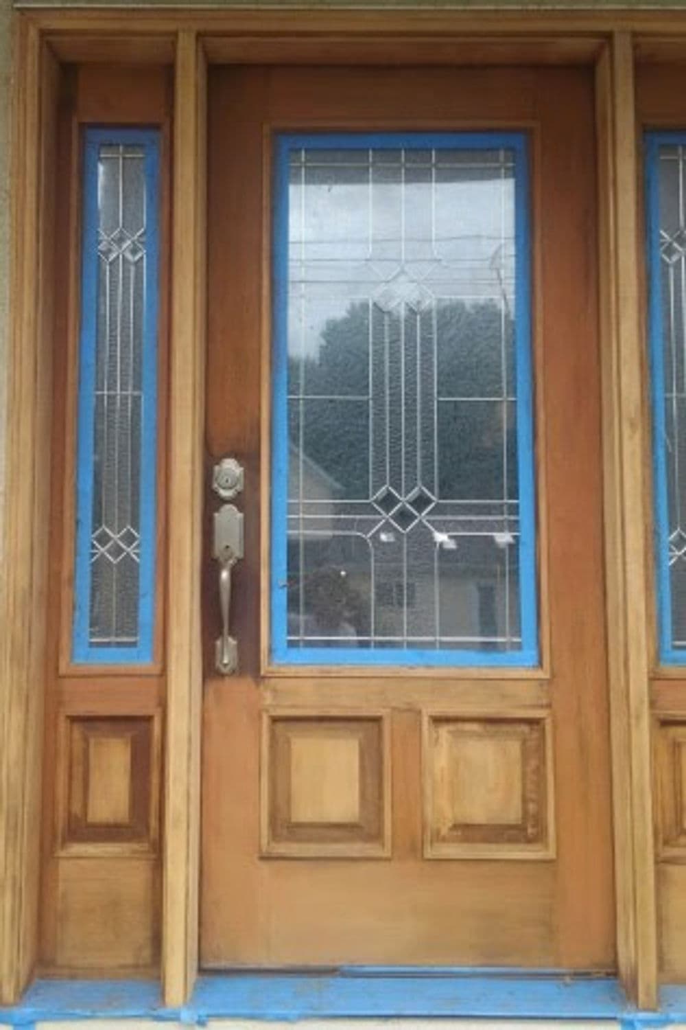 Wooden front door with decorative glass panels and blue accents.