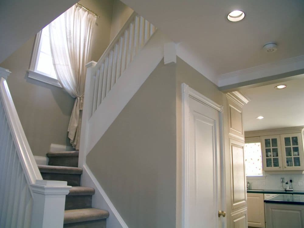 Bright, welcoming interior of a stairway leading to a kitchen with white cabinetry.