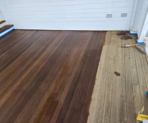 Wooden deck partially stained, showing a contrast between darker finished boards and lighter unfinished boards.