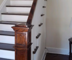 Wooden staircase with white risers, dark treads, and a polished wood handrail in a residential interior.